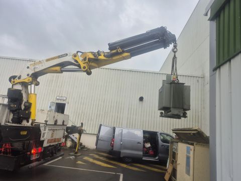 Levage d’un transformateur devant un bâtiment professionnel